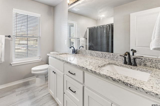 bathroom featuring walk in shower, vanity, a healthy amount of sunlight, and toilet