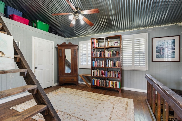 interior space with ceiling fan, dark hardwood / wood-style flooring, lofted ceiling, and wooden walls