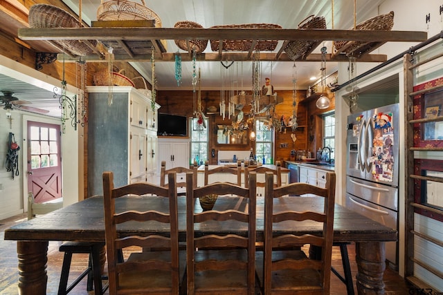 dining room featuring ceiling fan, sink, and wooden walls