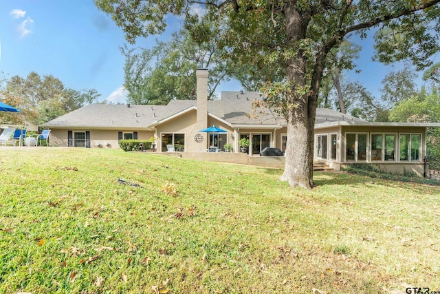 back of house featuring a yard and a sunroom