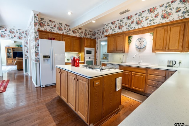 kitchen with hardwood / wood-style floors, beamed ceiling, sink, a center island, and white appliances