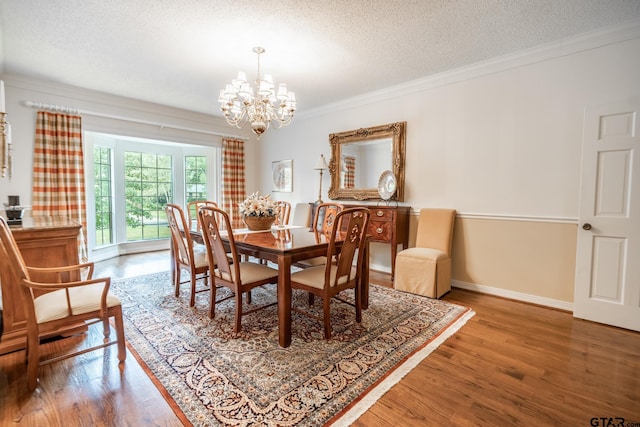 dining area with an inviting chandelier, ornamental molding, a textured ceiling, and hardwood / wood-style flooring