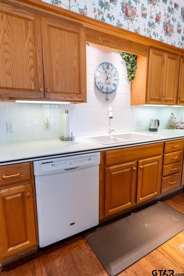 kitchen featuring dishwasher, sink, dark wood-type flooring, and backsplash