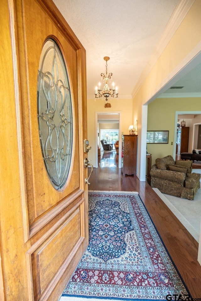 foyer featuring hardwood / wood-style flooring, crown molding, and a chandelier