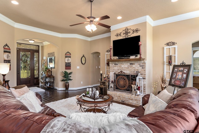 living room with a fireplace, ceiling fan, dark hardwood / wood-style floors, and crown molding