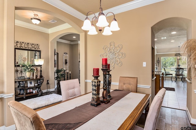 dining area with a chandelier, wood-type flooring, and crown molding