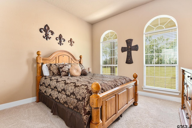 bedroom with a textured ceiling, light carpet, and lofted ceiling