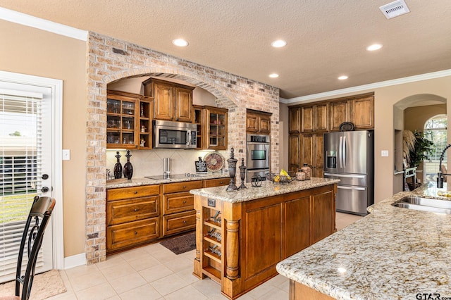 kitchen with stainless steel appliances, a textured ceiling, sink, and a center island