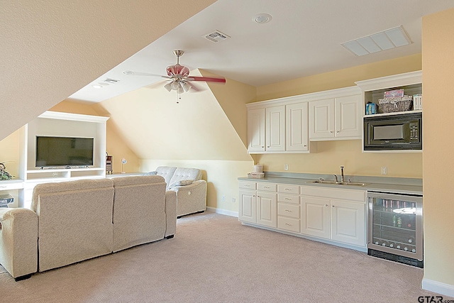 interior space featuring wine cooler, vaulted ceiling, black microwave, sink, and white cabinetry