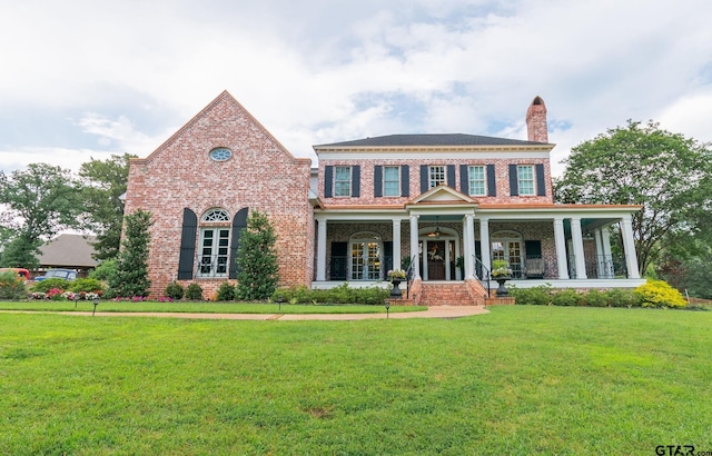 colonial house featuring covered porch and a front yard