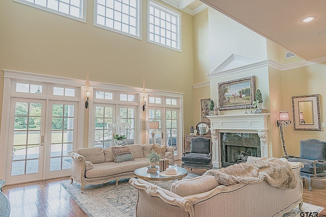 living room featuring crown molding, a fireplace, a high ceiling, and french doors