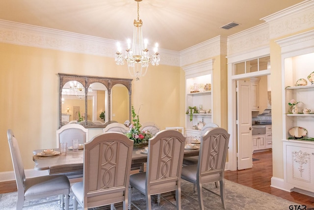 dining room with built in features, ornamental molding, dark hardwood / wood-style floors, and an inviting chandelier