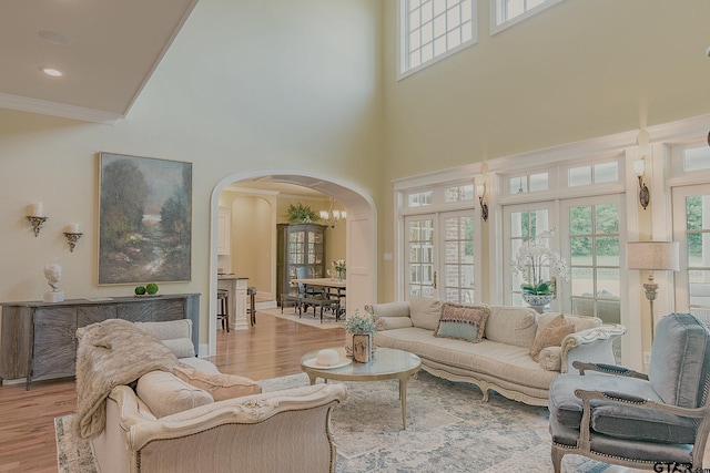 living room with crown molding, light hardwood / wood-style flooring, a high ceiling, and french doors