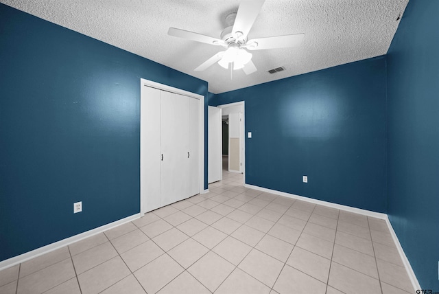 unfurnished bedroom with a textured ceiling, light tile patterned floors, ceiling fan, and a closet