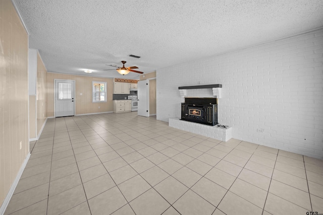 unfurnished living room featuring a textured ceiling, light tile patterned floors, ceiling fan, and brick wall