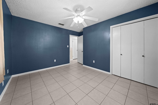 unfurnished bedroom with a textured ceiling, ceiling fan, and a closet