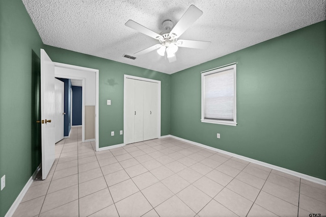 unfurnished bedroom with light tile patterned floors, ceiling fan, a textured ceiling, and a closet