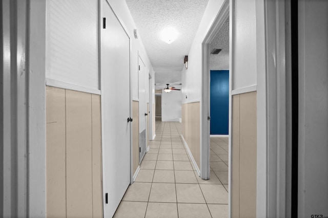 corridor with a textured ceiling and light tile patterned flooring