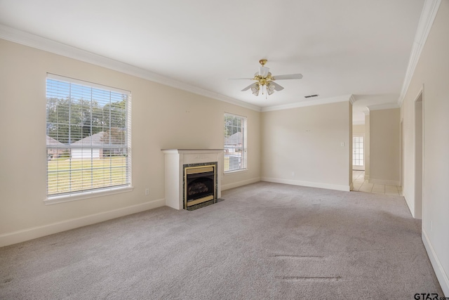 unfurnished living room featuring a fireplace, light colored carpet, ceiling fan, and crown molding