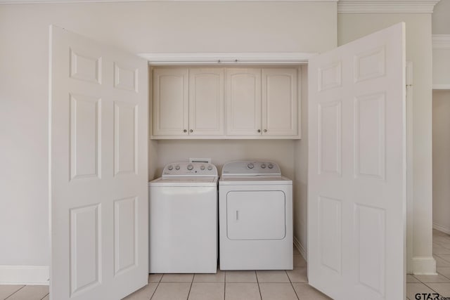 laundry area featuring cabinets, light tile patterned flooring, crown molding, and washer and clothes dryer