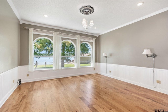 spare room with light hardwood / wood-style flooring, a textured ceiling, and plenty of natural light