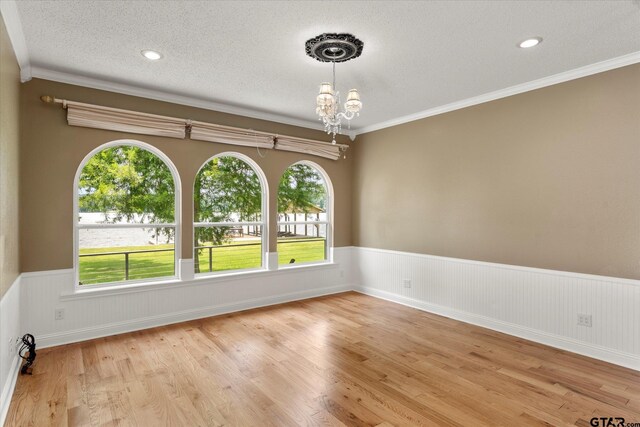 89 Eagle Cv, Mount Vernon, TX 75457 - unfurnished room featuring a wainscoted wall, a chandelier, light wood-style floors, crown molding, and a textured ceiling