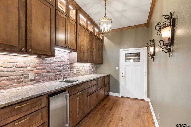 kitchen with light hardwood / wood-style floors, sink, light stone countertops, backsplash, and crown molding