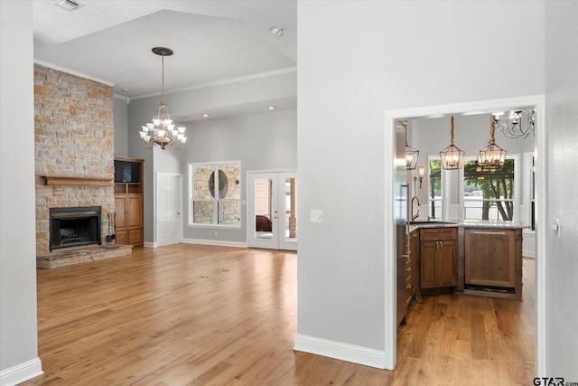 89 Eagle Cv, Mount Vernon, TX 75457 - unfurnished living room with a chandelier, a towering ceiling, light wood-style floors, a sink, and crown molding