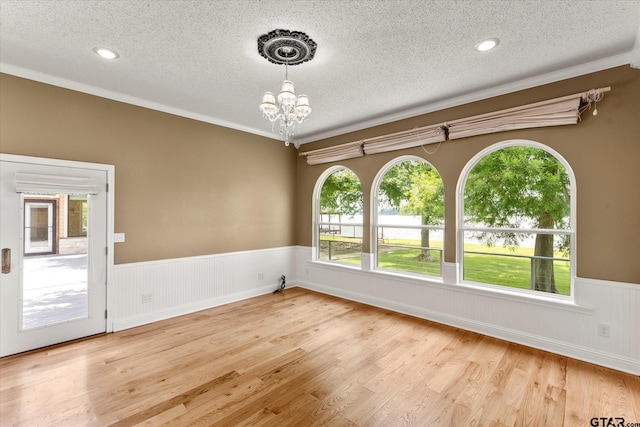 89 Eagle Cv, Mount Vernon, TX 75457 - empty room with a textured ceiling, wainscoting, a chandelier, ornamental molding, and wood finished floors