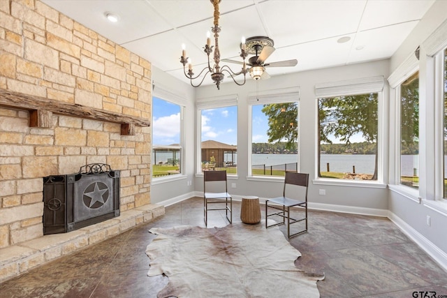 sunroom with a stone fireplace, a healthy amount of sunlight, a chandelier, and a water view