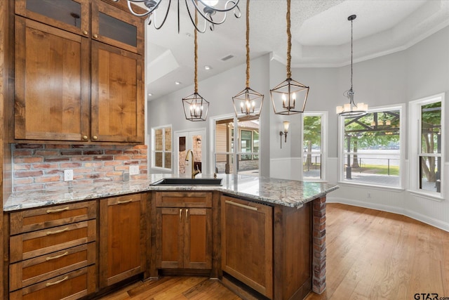89 Eagle Cv, Mount Vernon, TX 75457 - kitchen with a chandelier, a sink, brown cabinets, a peninsula, and a high ceiling
