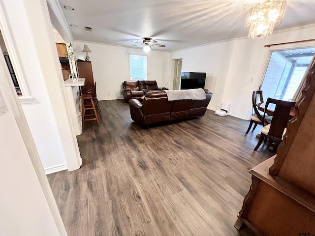 living room with dark hardwood / wood-style flooring, ceiling fan with notable chandelier, and ornamental molding