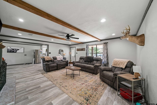 living room featuring a textured ceiling, light hardwood / wood-style floors, beamed ceiling, and ceiling fan