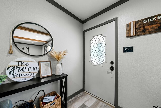 entryway with ornamental molding and light hardwood / wood-style flooring