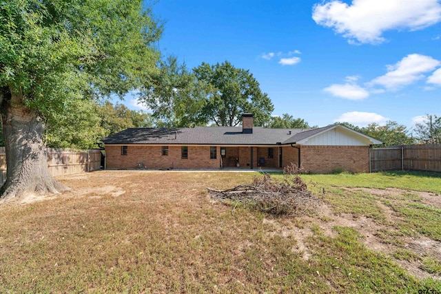 back of property with a yard and a patio area