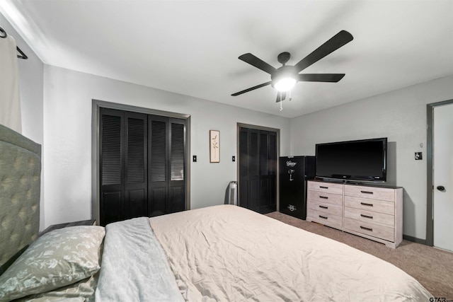 carpeted bedroom featuring ceiling fan and multiple closets