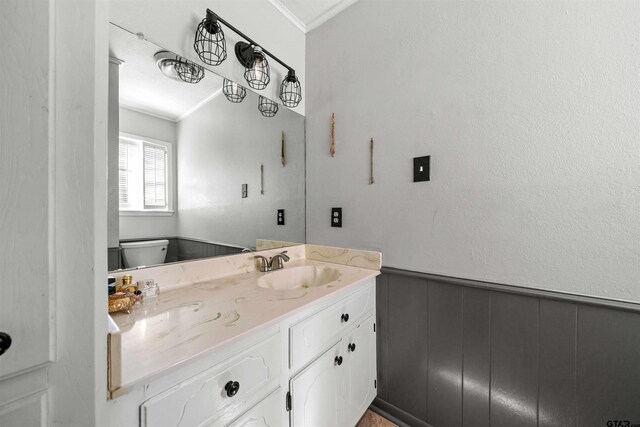 bathroom featuring toilet, vanity, wooden walls, and crown molding