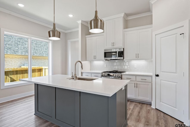 kitchen with pendant lighting, sink, white cabinetry, a kitchen island with sink, and stainless steel appliances