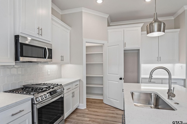 kitchen featuring sink, white cabinets, hanging light fixtures, and appliances with stainless steel finishes