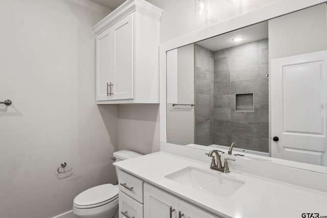 bathroom with toilet, vanity, and a tile shower