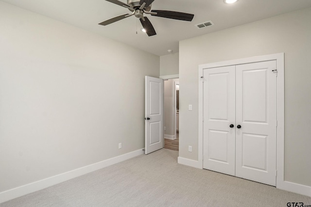 unfurnished bedroom with light colored carpet, a closet, and ceiling fan