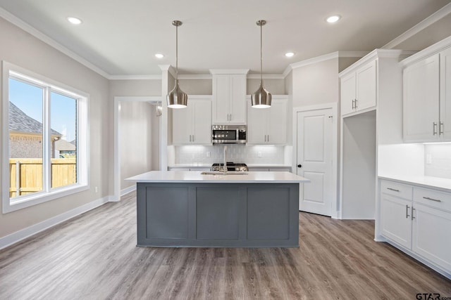 kitchen with decorative light fixtures, white cabinets, and a kitchen island with sink