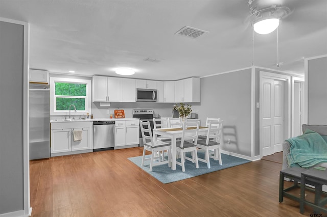 kitchen with a sink, visible vents, light countertops, white cabinets, and appliances with stainless steel finishes