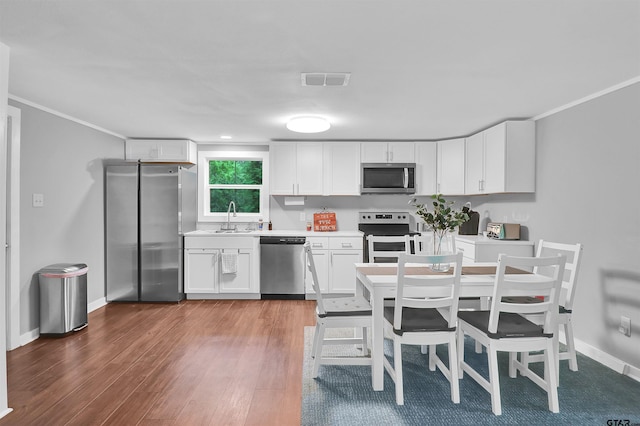 kitchen featuring white cabinetry, a sink, appliances with stainless steel finishes, visible vents, and wood finished floors