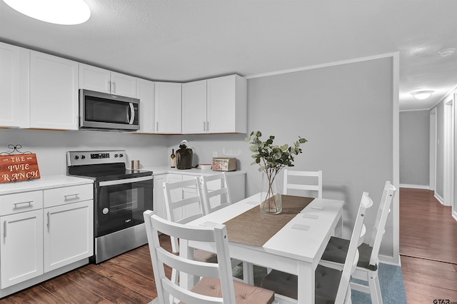 kitchen featuring white cabinetry, stainless steel appliances, light countertops, and dark wood-style floors