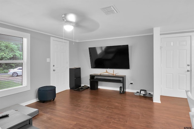 living area with crown molding, visible vents, ceiling fan, and wood finished floors