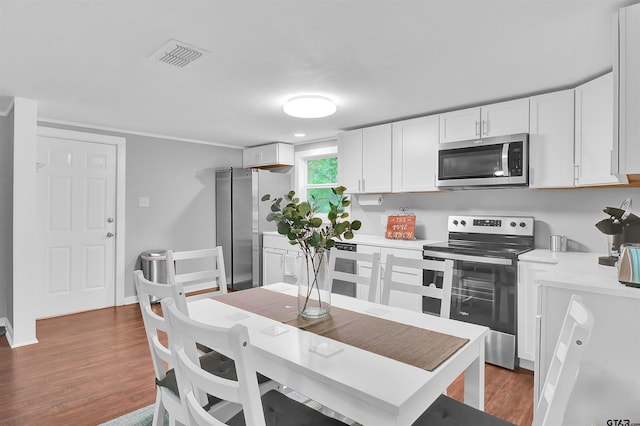 kitchen with wood finished floors, appliances with stainless steel finishes, light countertops, white cabinets, and visible vents