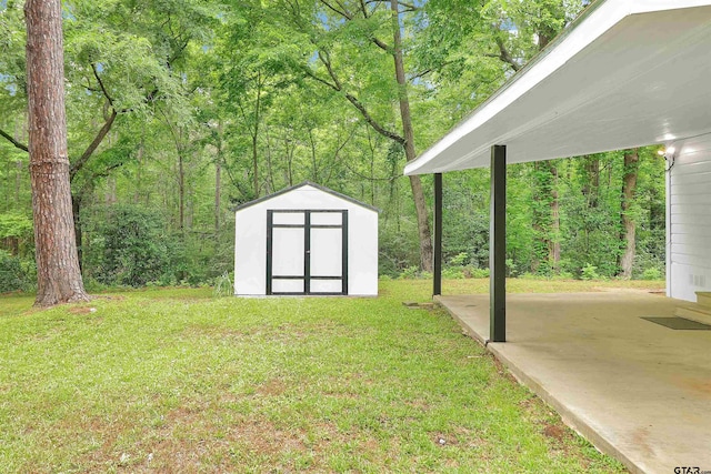 view of yard featuring a patio, an outbuilding, a wooded view, and a storage shed