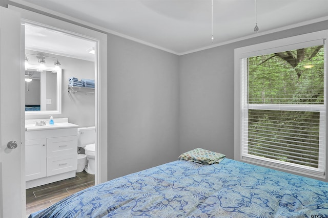 bedroom with wood finished floors, ornamental molding, and a sink
