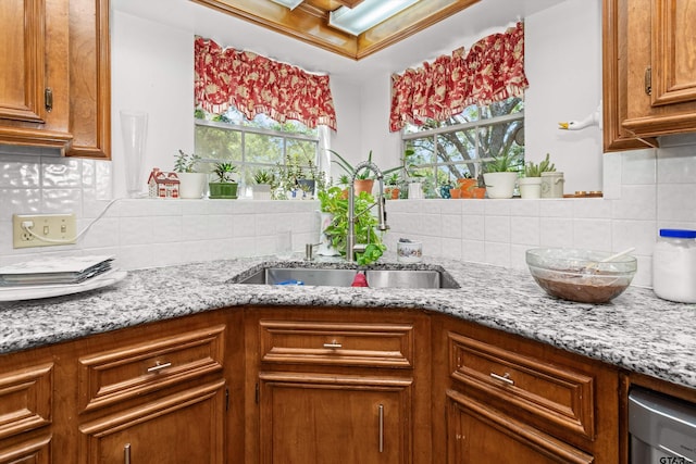 kitchen with plenty of natural light, sink, light stone counters, and tasteful backsplash